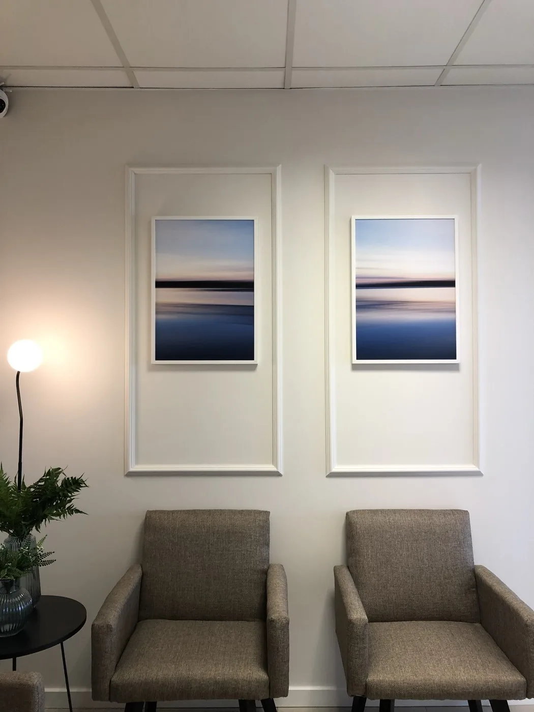 Sala de espera com quadros, plantas e poltronas confortáveis